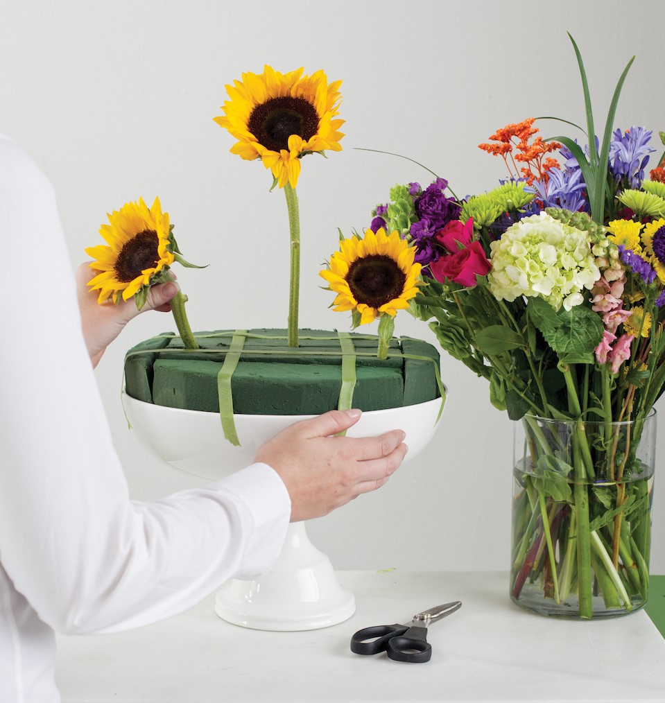 securing three sunflowers to form a triangle in the floral foam